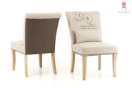 Stuhl dick gepolstert mit Stoff und bronzefarbenen Nieten mit robust wirkenden Holzbeinen